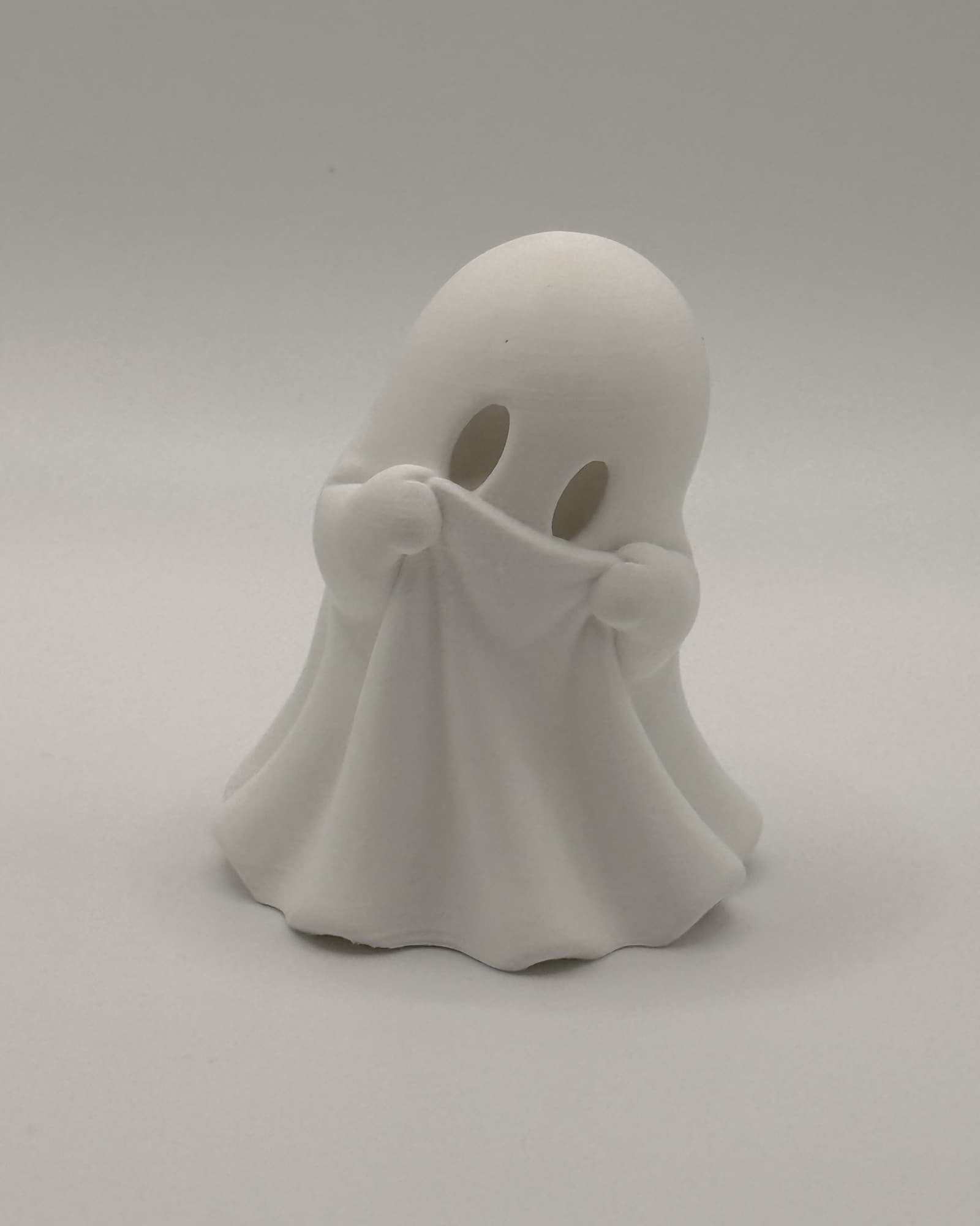 Boo, a small white ghost, holding his sheet up to his eyes
