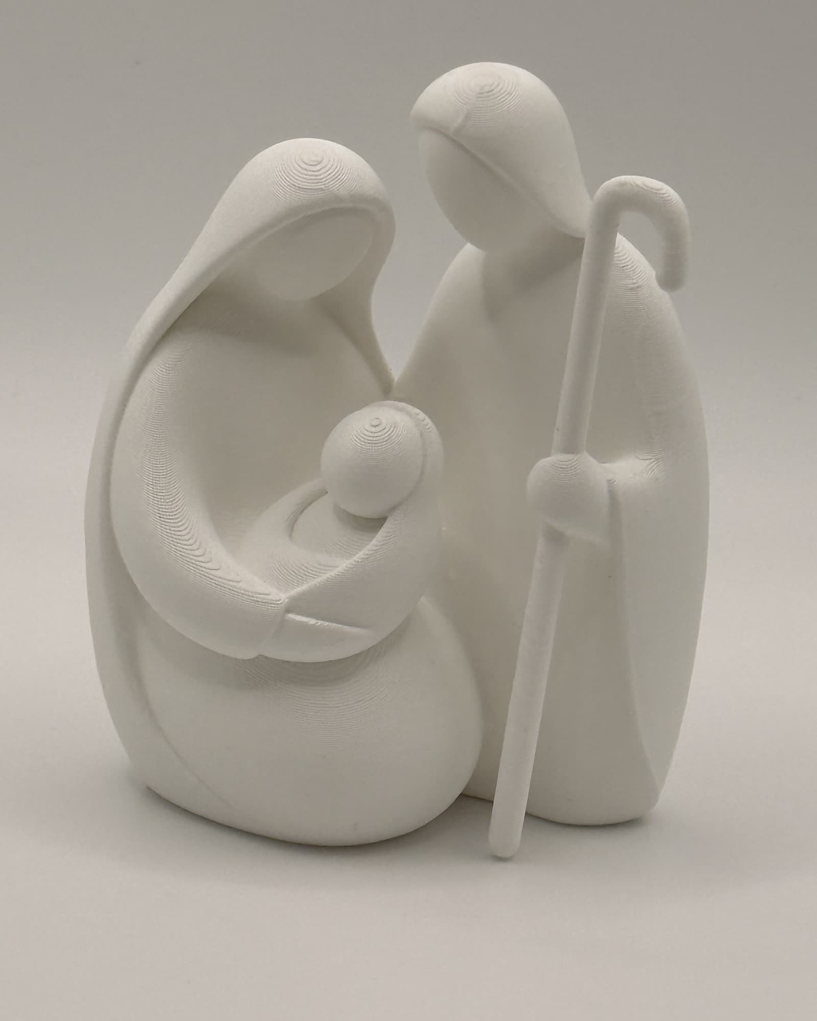 The Holy Family in white: Mary holding the baby, Joseph beside them with his staff