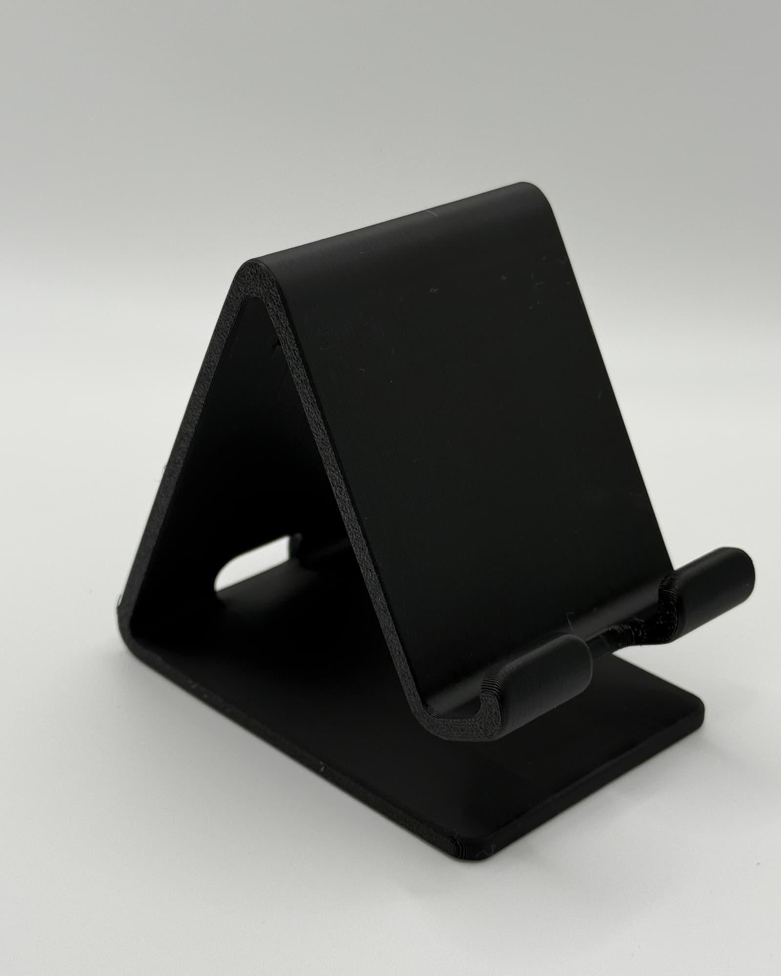 The Desk Perch, a black phone stand with a small front ledge, seen from the front